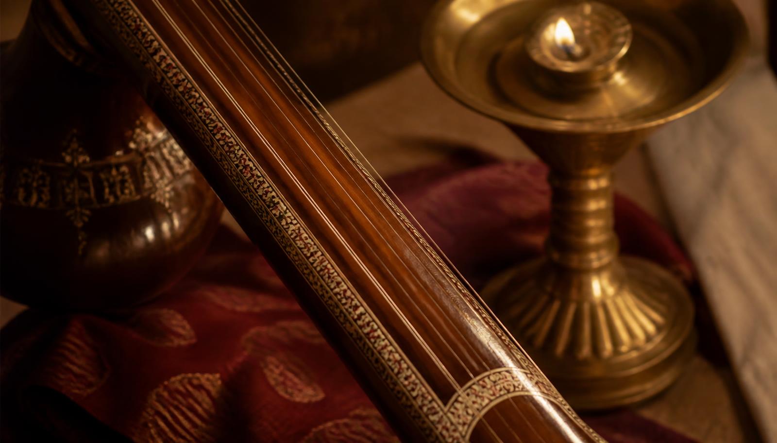 Tanpura strings beside a brass lamp in warm amber light